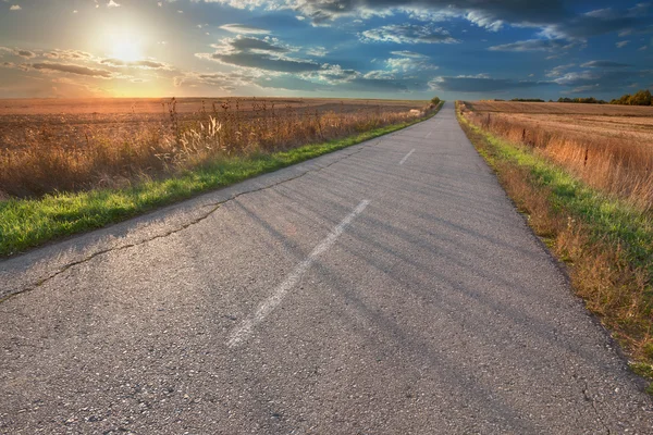 Guidare su una strada asfaltata vuota al tramonto — Foto Stock
