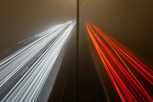 在一个有雾的夜晚公路上的光迹 — 图库照片