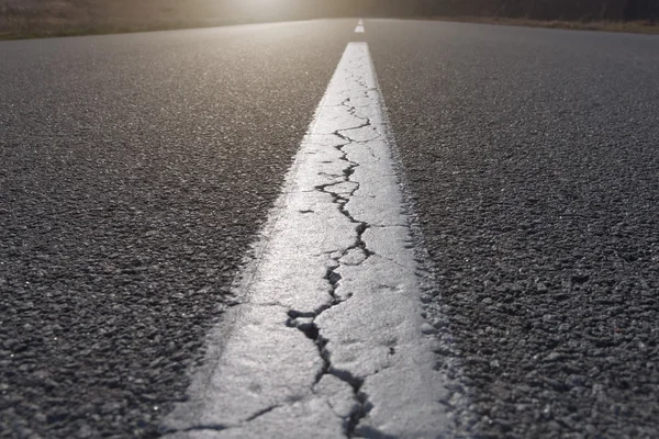 Rechte lijn op asfalt vol scheuren — Stockfoto
