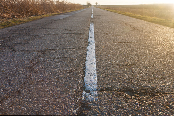 Заброшенная асфальтовая дорога, полная трещин
