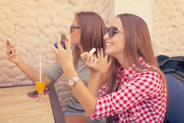 Две девушки смеются и ремонтируют макияж — стоковое фото