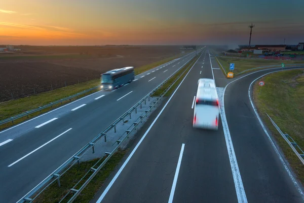 動きの 2 つのバスは夕暮れ時高速道路にぼかし — ストック写真