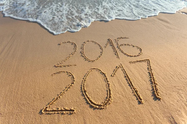 Digits 2017 and 2016 on coast sand at sunset — Stock Photo, Image
