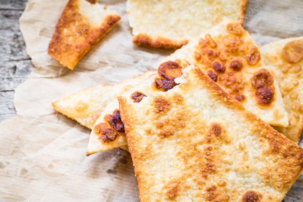 Crunchy pizza dough triangles on rustic background  