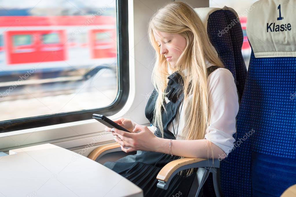 girl sitting in train and holding tablet