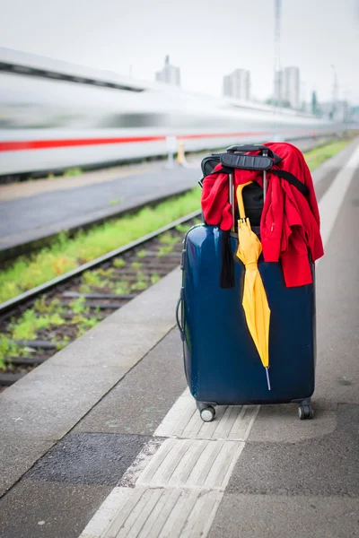 Suitcase with umbrella on platform — Stock Photo, Image