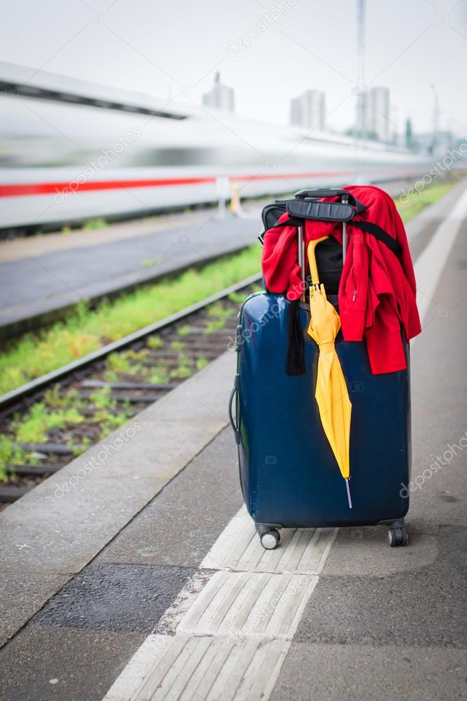 Suitcase with umbrella on platform