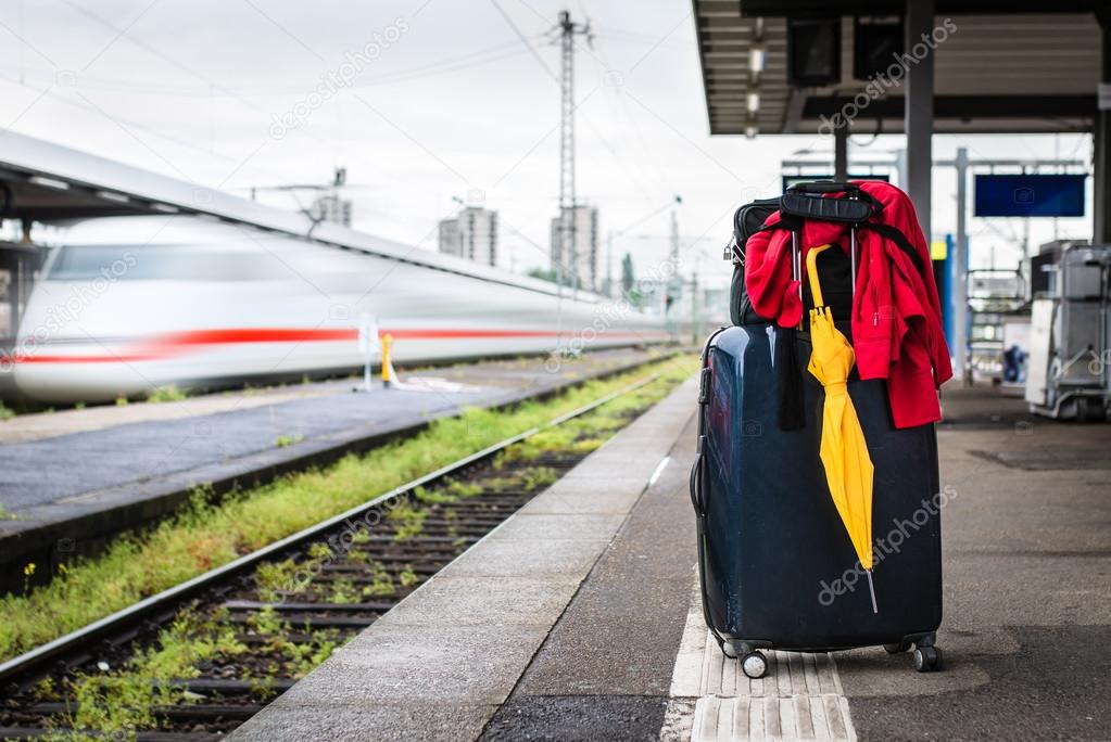 Suitcase with umbrella on platform