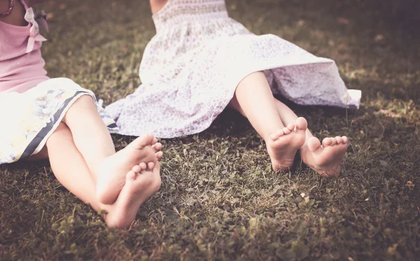 Bare legs of little girls on meadow — Stock Photo, Image