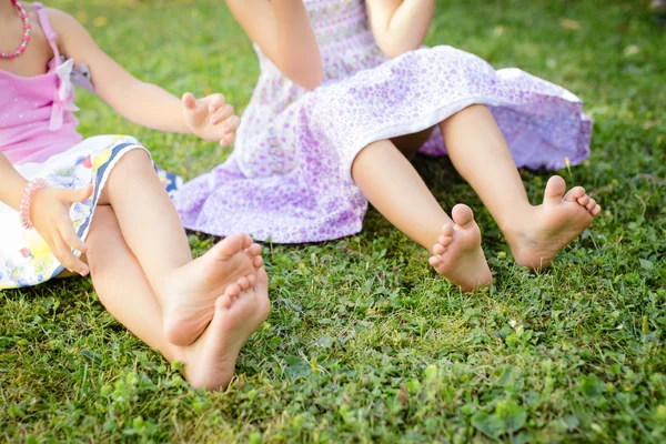 Cute bare legs of little girls on meadow — Stock Photo, Image