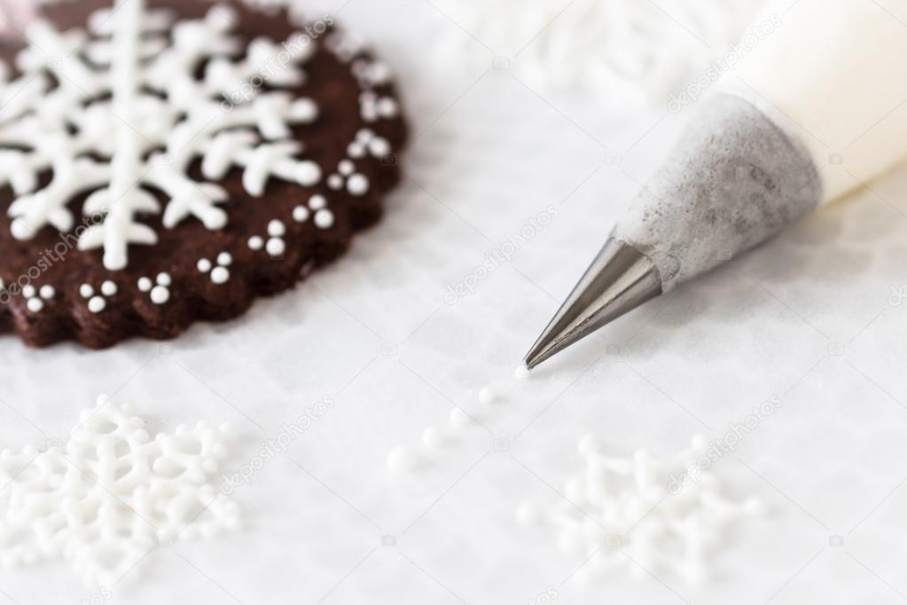 Piping white snowflakes with royal icing