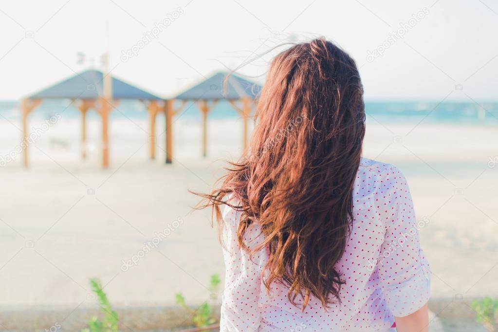 Lonely girl looking at empty beach