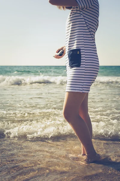 Flickan står i vattnet på stranden — Stockfoto