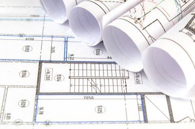 İnşaat halindeki binanın çizimleri katlanmış ve yerleştirilmiş çizimin bir parçasının üzerine serilmiş..