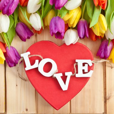 Kırmızı kalp üzerinde ahşap harflerle seviyorum