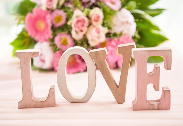 LOVE in front of flower bouquet — Stok fotoğraf