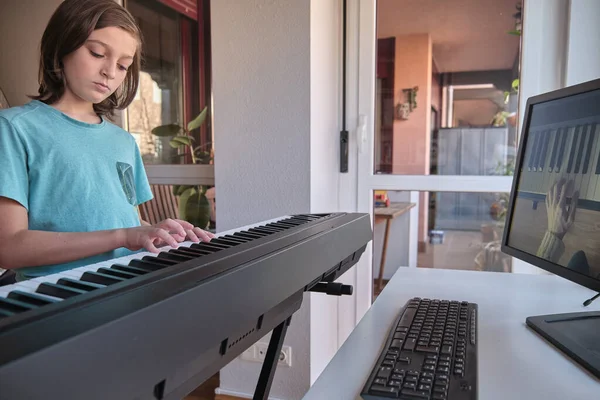 Evde online ders sırasında klasik dijital piyano çalan genç müzisyen, karantina sırasında sosyal mesafe, kendini izole etme, online eğitim kavramı