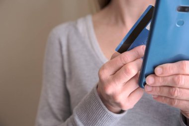 İnternetten alışveriş konsepti. Kadın kredi kartını tutarken akıllı telefonunu kart bilgilerini girmek ve ödeme yapmak için kullanıyor. Yaşam tarzı ve teknoloji. Kapat..