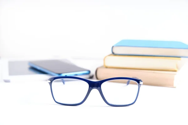 Beyaz masada arka planda kitap ve tablet olan gözlük. Gözlüklere odaklan, Ebook kitap konseptine karşı