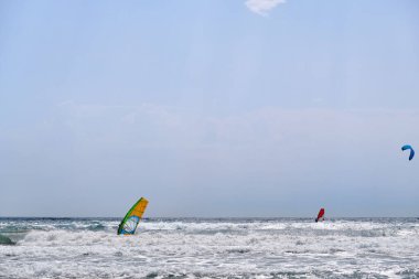 İnsanlar sahilde sörf yapıyor.