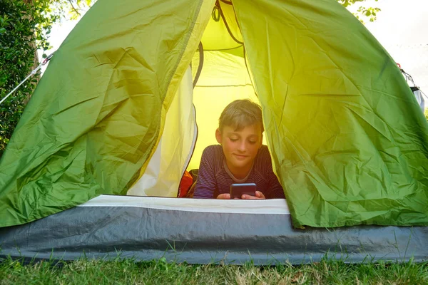 Tonåring som använder mobilen i ett tält — Stockfoto
