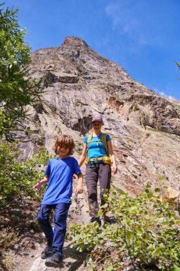Gülümseyen anne ve oğul bir dağdan iniyorlar. İtalyanlar Alpler