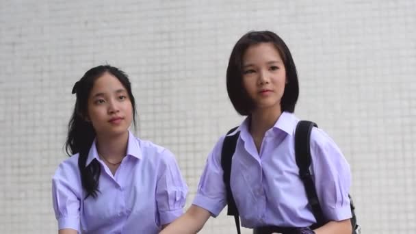 Χαριτωμένο Ασιάτης/ισσα Ταϊλανδός/ή φοιτητής ζευγάρι σε σχολείο στολή μιλάει και παίζοντας κρατώντας τα χέρια με ένα χαρούμενο χαμόγελο μαζί σε λευκό φόντο — Αρχείο Βίντεο