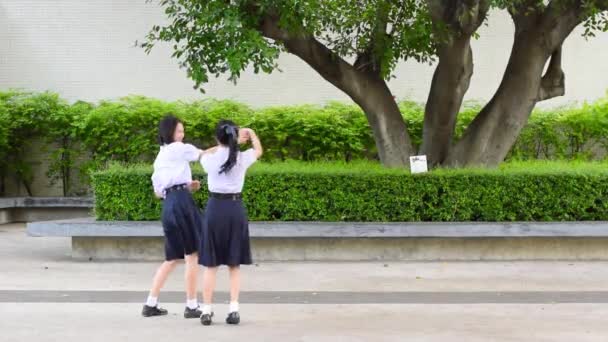 Söt asiatiska thailändska höga skolflickor student paret i skoluniform har roligt att spela jagar och fånga en docka med sin elev vän — Stockvideo