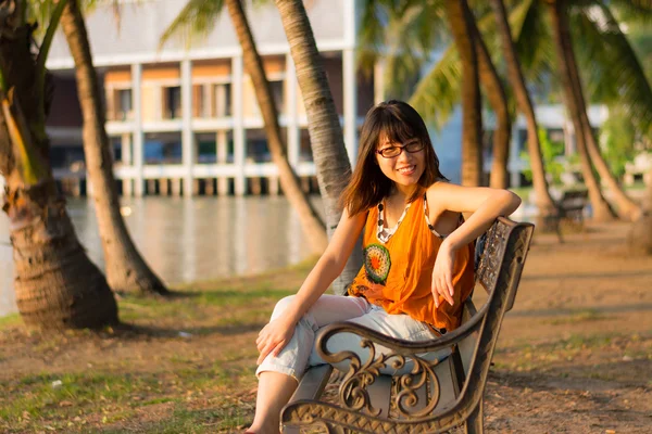 Nettes thailändisches Mädchen entspannt sich am Flussufer im Schatten der Palmen — Stockfoto