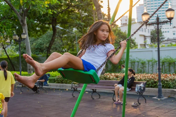 Children welfare. Cute Thai girl playing a swing — Stock Photo, Image