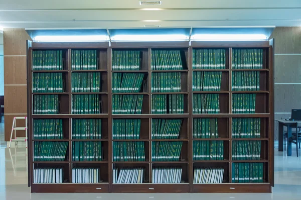 Raden av gröna böcker i bokhyllan i ett bibliotek, full av kunskap — Stockfoto