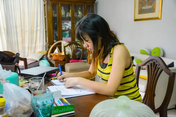 Tailandês menina da faculdade está ocupado estudando em uma mesa bagunçada — Fotografia de Stock