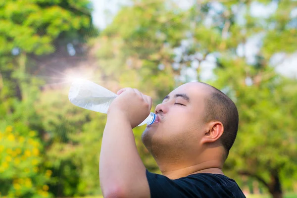 Азіатський лисою головою хлопця є питної води з спрагу з легкої вплив на пляшки — стокове фото