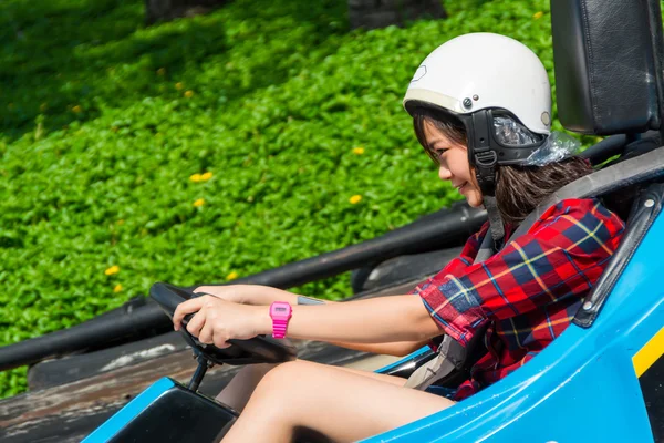 Cute Asian Thai girl is driving Go-kart car with speed in a playground racing track. Go kart is a popular leisure motor sports. — Stock Photo, Image