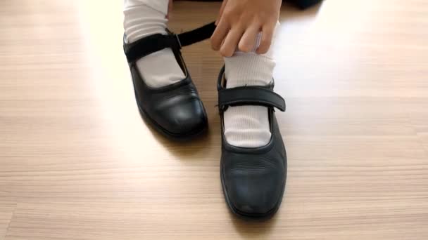 Asiática tailandesa colegiala estudiante en uniforme de escuela secundaria está usando sus zapatos de cuero negro en lindo diseño de moda de educación en el salón de clases de piso de madera en calidad HD 1920x1080 — Vídeo de stock