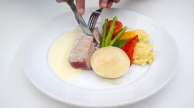 Kremalı sos soslu Tuna Steak Gurme mutfağı. Ana yemek olarak garnitür salatası ile ton balığı biftek yiyen bir kişi.
