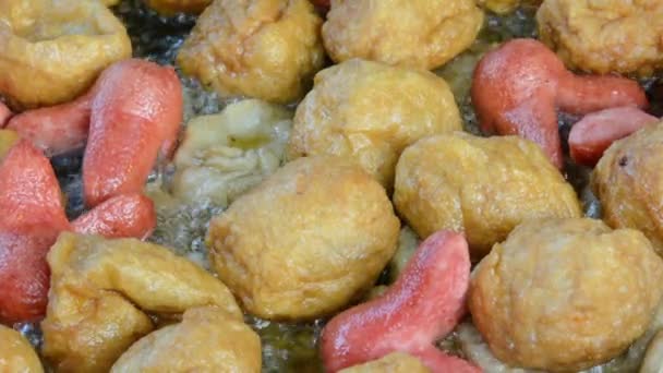 Close-up van varkensvlees worst, gebakken tofu, en vis ballen eten zijn diepe gebakken in de hete kokende olie te koop in een wok in Thailand open supermarkt. (1920 x 1080 Hd) — Stockvideo