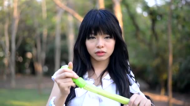 Ganska asiatiska Thai flicka i vintage mode kläder klänning blåser en såpbubblor i parken för att påminna om sin barndom leksak med söt glad uttryck — Stockvideo