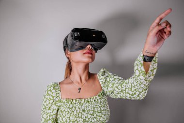 Asyalı kadın evde sanal gerçeklik cihazına bakıyor. Geliştirilmiş gerçeklik, oyun, gelecekteki teknoloji kavramı.