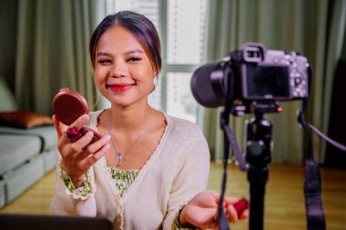 Genç ve güzel Asyalı kadın profesyonel güzellik blogcusu veya blog yazarı sosyal medyada paylaşmak için makyaj yapıyor.