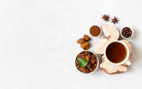 Mushroom chaga drink with coffee on a white background. Coffee beans, chopped pieces of chaga, anise and a cup with a healthy drink. Copy space, view from above.