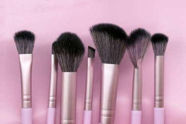 set of different makeup brushes on a pink background