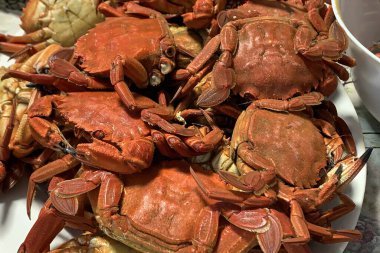 Bir tabak kırmızı yengeç. Tabakta en az altı tane yengeç var.