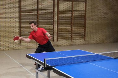 Profesyonel bir oyuncu, antrenman sırasında masa tenisi oynarken forehand top-spin yapar.