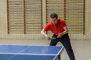 Profesyonel bir oyuncu, antrenman sırasında masa tenisi oynarken ters takla atar.