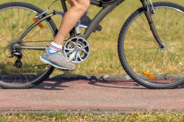 Bir adam yolda bisiklet sürüyor, yan görüş, yakın plan.