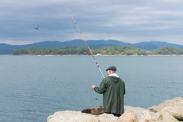 Uomo anziano pesca sull'oceano — Foto Stock