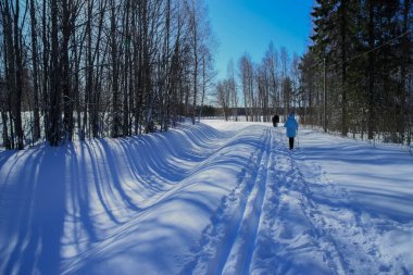 Bir adam orman boyunca sopalarla yürür..