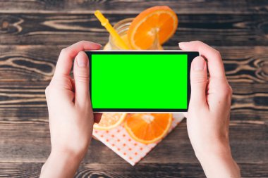 Portakal fotoğrafta eller. Yeşil ekran. Teknoloji kavramı