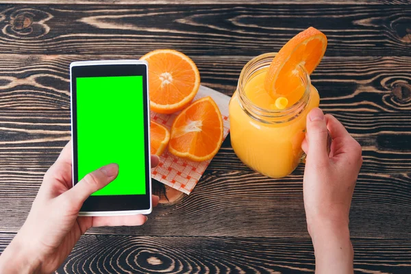 Mujer usando teléfono móvil contra naranjas de frutas. Concepto de tecnología . — Foto de Stock